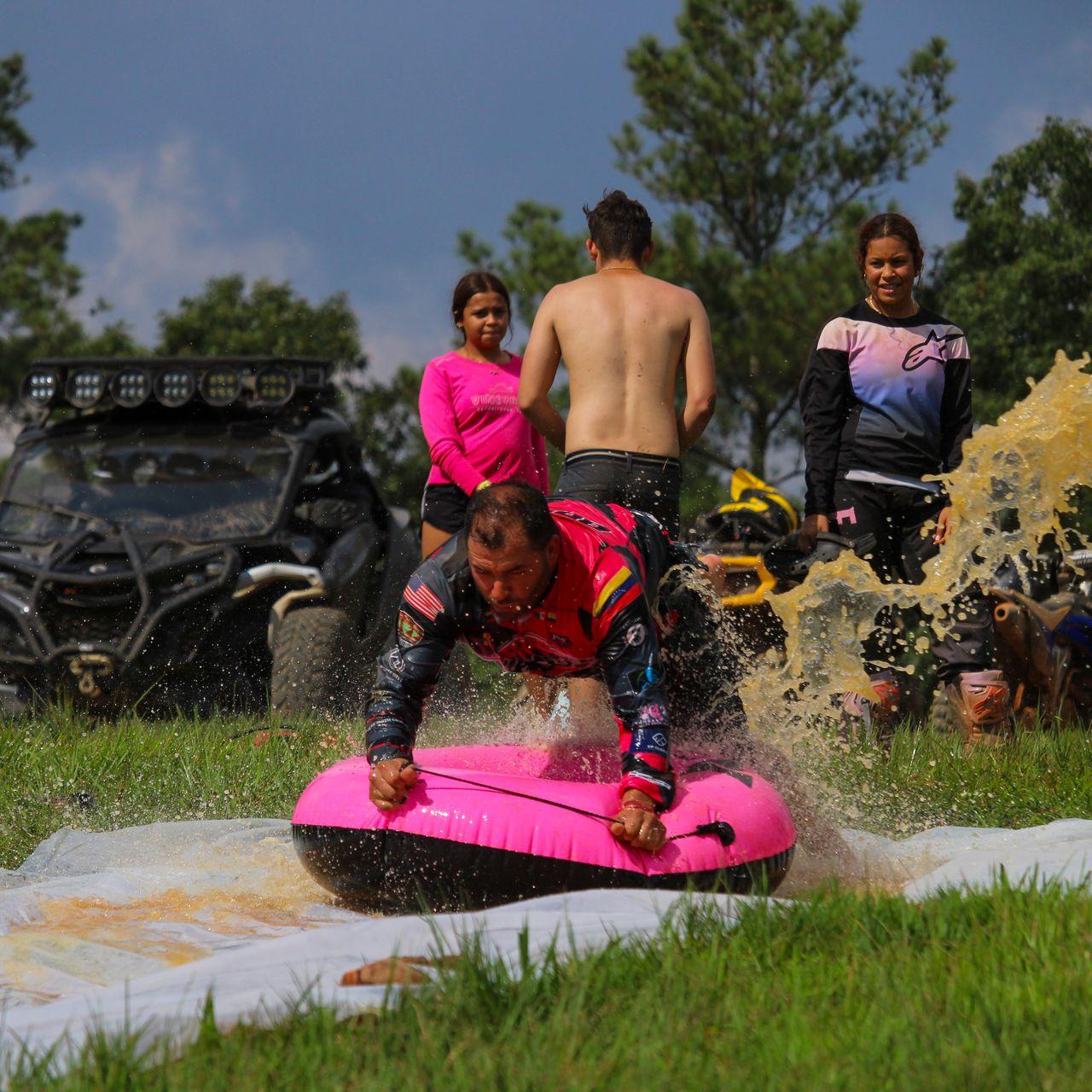 Kids on the slip-n-slide getting splashed at a family event day.