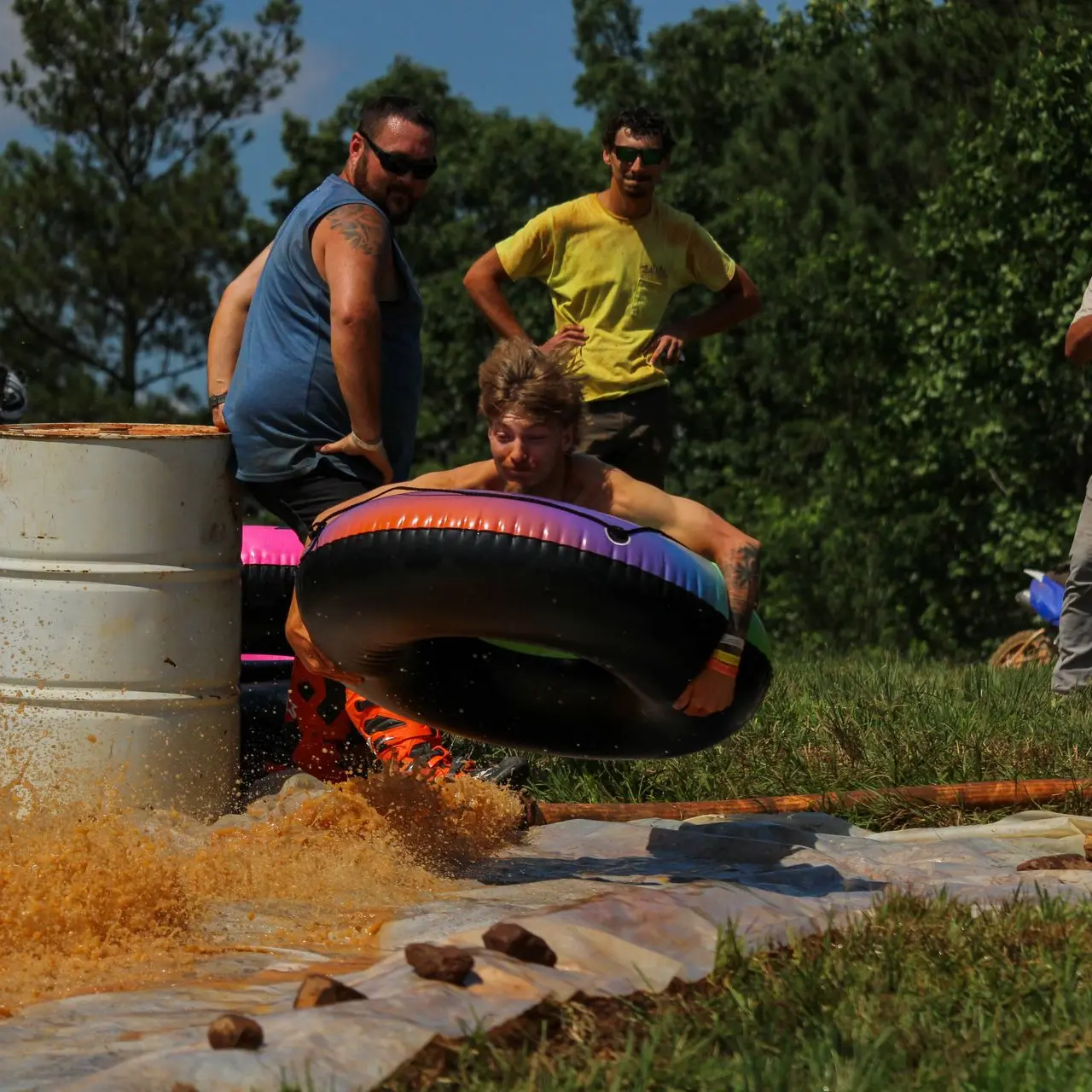 Rider launching off a barrel into an inner tube at a slip-n-slide event.